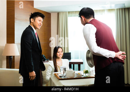 Chinois asiatique prix waiter serving food in hôtel suite Banque D'Images