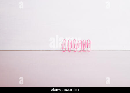 Fournitures de bureau.La composition de ligne multi-colored trombones sur fond rose pastel, papier coloré.isolé clips.copie espace.La composition créative.Le minimalisme concept.Matériel d'art et d'artisanat Banque D'Images