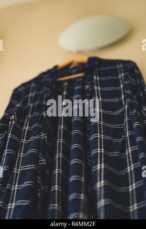 Chemise bleue à rayures accroché au mur dans le Salon - objet isolé, en partie floue, vintage film Modifier Banque D'Images