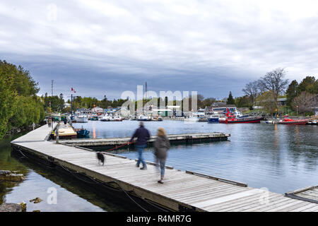 Les gens qui marchent le long d'une jetée par Little Tub et ville de Tobermory au crépuscule,Ontario, Canada Banque D'Images