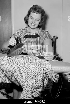 Une femme dans un fauteuil roulant et d'une planche sur une planche à repasser, ca. 1960. Banque D'Images