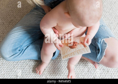 Baby Girl holding photographie dans les genoux de sa mère Banque D'Images