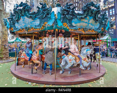 Les enfants équitation un carrousel dans le village d'hiver au Bryant Park, à Manhattan, New York City. Banque D'Images