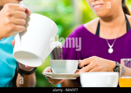 Asian couple having coffee sur porche d'accueil Banque D'Images
