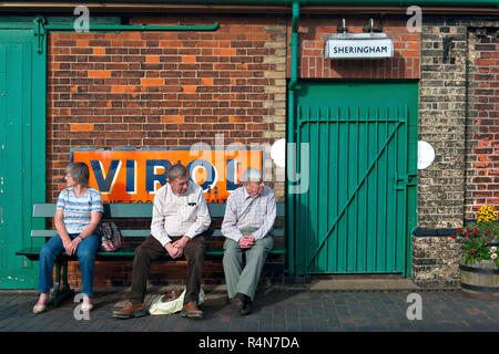 Trois aînés se détendent sur la plate-forme de la gare de Sheringham sur le chemin de fer du patrimoine nord de Norfolk. Banque D'Images