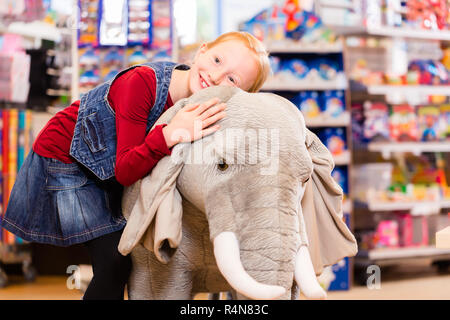 Petite fille dans magasin de jouets câlins avec animal en peluche Banque D'Images