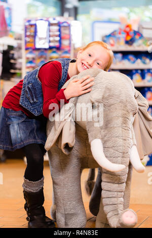 Petite fille dans magasin de jouets câlins avec animal en peluche Banque D'Images