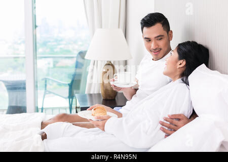 Couple asiatique se prélasser dans le lit au matin Banque D'Images