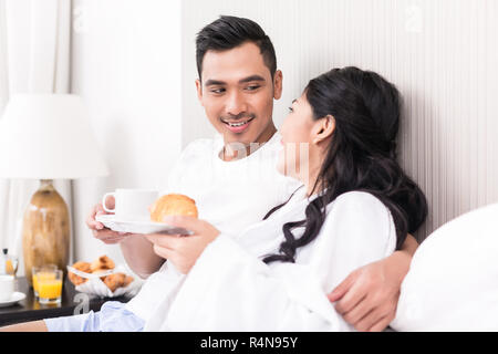 Couple asiatique se prélasser dans le lit au matin Banque D'Images