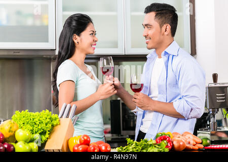 Asian couple drinking red wine in kitchen Banque D'Images