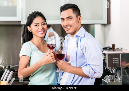 Asian couple drinking red wine in kitchen Banque D'Images