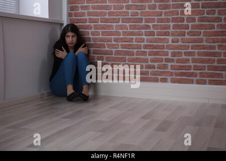 Craint Woman Sitting On The Corner Banque D'Images