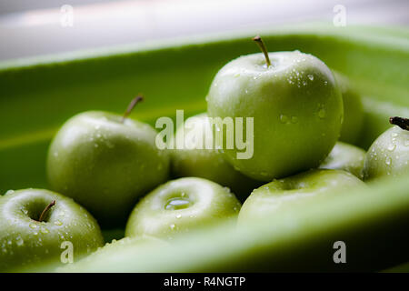 La pomme verte dans un panier de lavage avec des gouttelettes d'eau sur leur peau. Banque D'Images