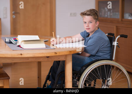 Garçon en fauteuil roulant à faire leurs devoirs Banque D'Images