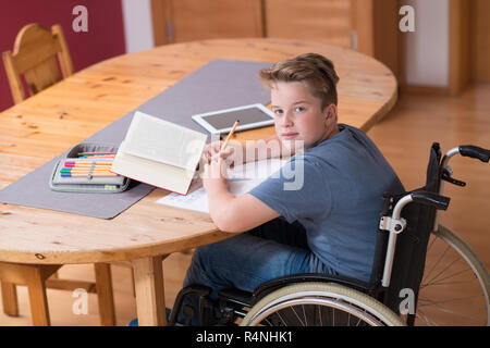 Garçon en fauteuil roulant à faire leurs devoirs Banque D'Images