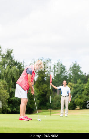 Senior woman practicing with golf pro Banque D'Images