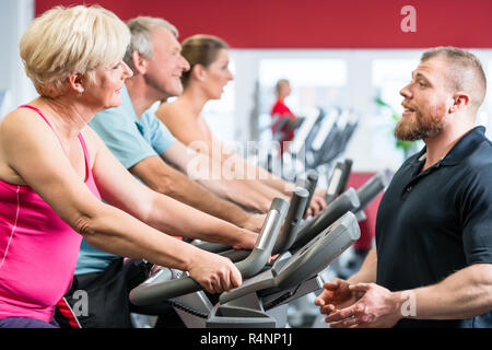 Entraîneur personnel indique à senior woman à propos de tourner dans la salle de sport Banque D'Images