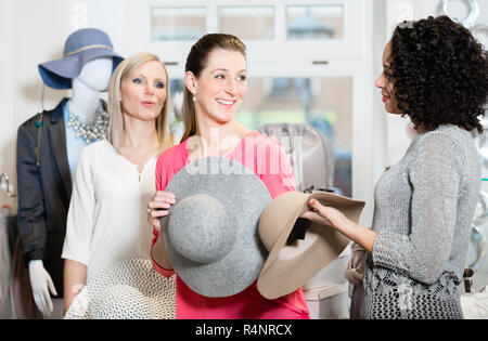 Des amies sur shopping essayer mesdames chapeaux et autres articles de mode Banque D'Images