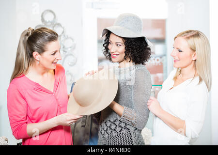 Des amies sur shopping essayer mesdames chapeaux et autres articles de mode Banque D'Images