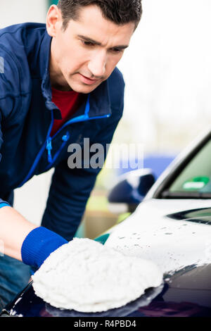 L'homme qui travaillent dur avec voiture de polissage microfibre blanche mitt Banque D'Images