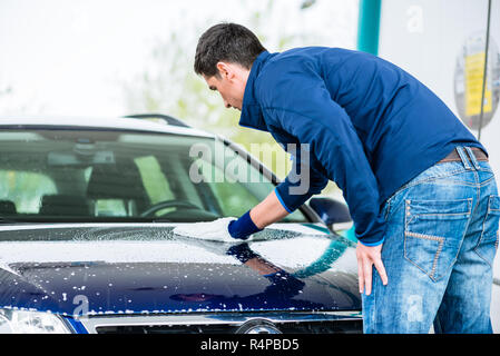 L'homme qui travaillent dur avec voiture de polissage microfibre blanche mitt Banque D'Images