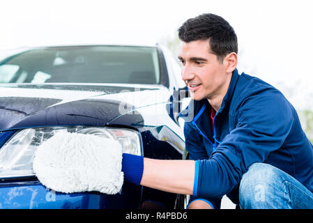 L'homme qui travaillent dur avec voiture de polissage microfibre blanche mitt Banque D'Images