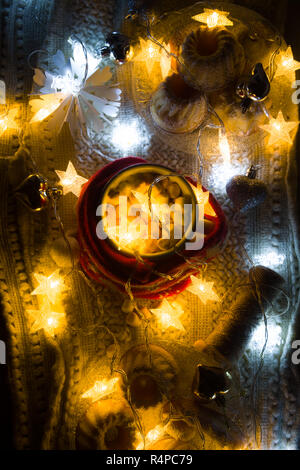 Chaud cacao mug avec décoration de Noël illumination, enroulée sur un textile d'hiver, sur une écharpe de laine, l'hiver à la maison anchristma photographie conceptuelle. Banque D'Images