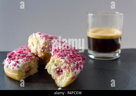 Donut avec remplissage de fraises coupées en deux et une tasse de café expresso Banque D'Images