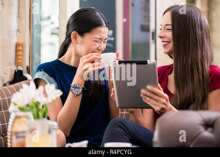 Deux jeunes femmes riant tout en utilisant une tablette Banque D'Images