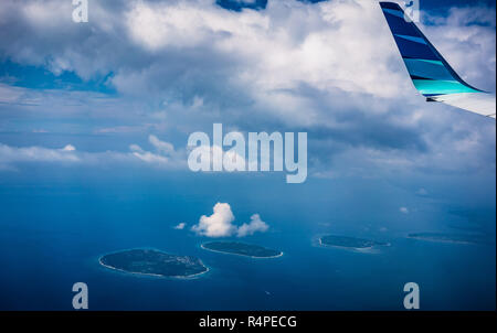 Vue depuis la fenêtre de l'avion à travers les nuages à tropical island Banque D'Images