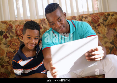 Jeu de garçon avec le père sur un ordinateur portable Banque D'Images