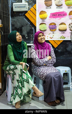 Les jeunes femmes malaisiennes dans Ice Cream Shop portant robe de Malaisie moderne typique, Ipoh, Malaisie. Banque D'Images