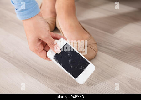 Woman picking Up The Broken Smart Phone Banque D'Images