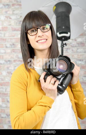 Jolie brunette woman with photo appareil photo en studio Banque D'Images