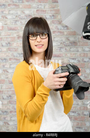 Jolie brunette woman with photo appareil photo en studio Banque D'Images