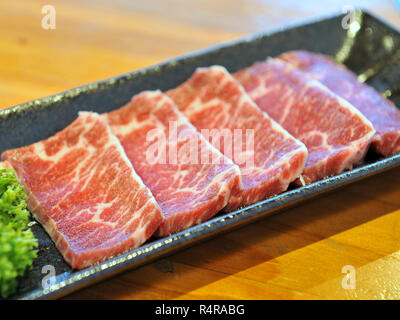 Tranches de boeuf cru frais sur plateau noir