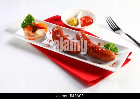 Saucisses Frites avec sauce chili et radis tranchés sur plateau blanc Banque D'Images