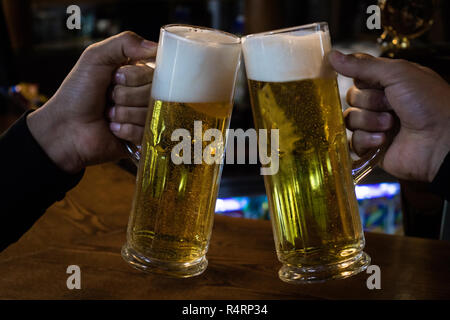 Cheers. Close-up of two men toasting avec de la bière au comptoir du bar Banque D'Images