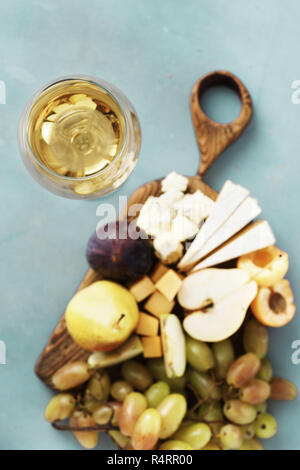 Verre de vin blanc avec des apéritifs vin. Fruits et fromage sur planche de bois sur fond de pierre. Hors-d'Vin Banque D'Images