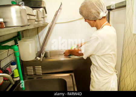 Femme chef et travailleur travaille à l'usine de crème glacée est de verser le lait pasteurisé et le lait de mélange de cuisine dans la préparation de la machine de pasteurisation. Banque D'Images