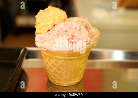 La crème glacée dans un cornet gaufré cup. Boule de fraise et citron de la crème glacée dans un cornet gaufré isolé sur fond de pâtisserie-shop. Doux, la saison d'été. Banque D'Images