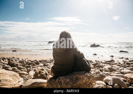 Une fille avec un sac à dos ou un touriste ou un voyageur dans la solitude admire une vue magnifique sur l'océan Atlantique au Portugal. Recherche de l'âme ou l'unité avec la nature. Banque D'Images