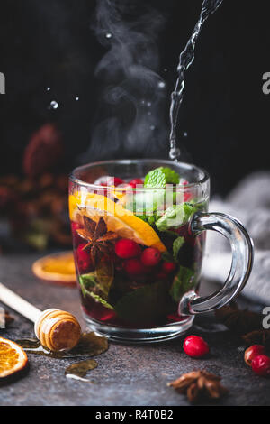 Fruits chaud thé avec des épices, d'orange et menthe. Verre vapeur tasse de thé, vin chaud aux canneberges canneberges épicée ou grog Banque D'Images