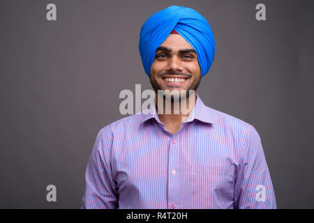 Beau jeune homme d'affaires indien portant turban contre ba gris Banque D'Images