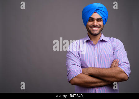 Beau jeune homme d'affaires indien portant turban contre ba gris Banque D'Images