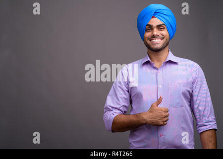 Beau jeune homme d'affaires indien portant turban contre ba gris Banque D'Images