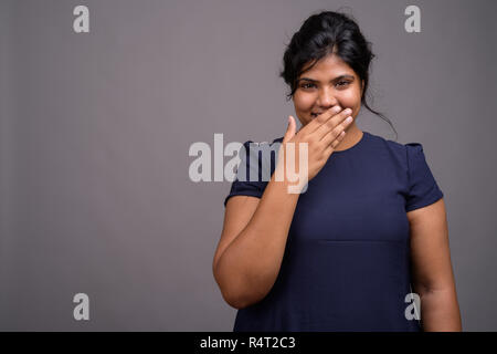 Les jeunes en surpoids belle femme indienne contre l'arrière-plan gris Banque D'Images