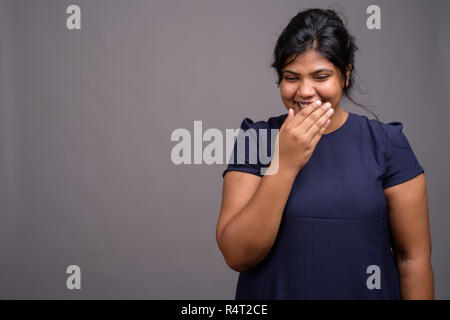 Les jeunes en surpoids belle femme indienne contre l'arrière-plan gris Banque D'Images