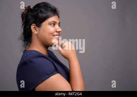 Les jeunes en surpoids belle femme indienne contre l'arrière-plan gris Banque D'Images