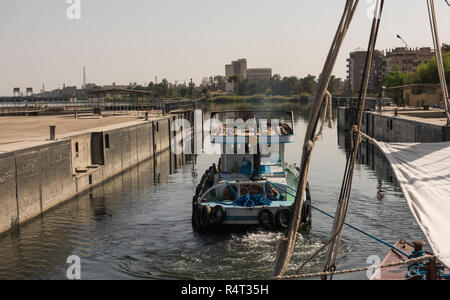 Petit remorqueur de remorquage d'un yacht de luxe sur le Nil en Egypte par ville paysage rural à Edfu Banque D'Images